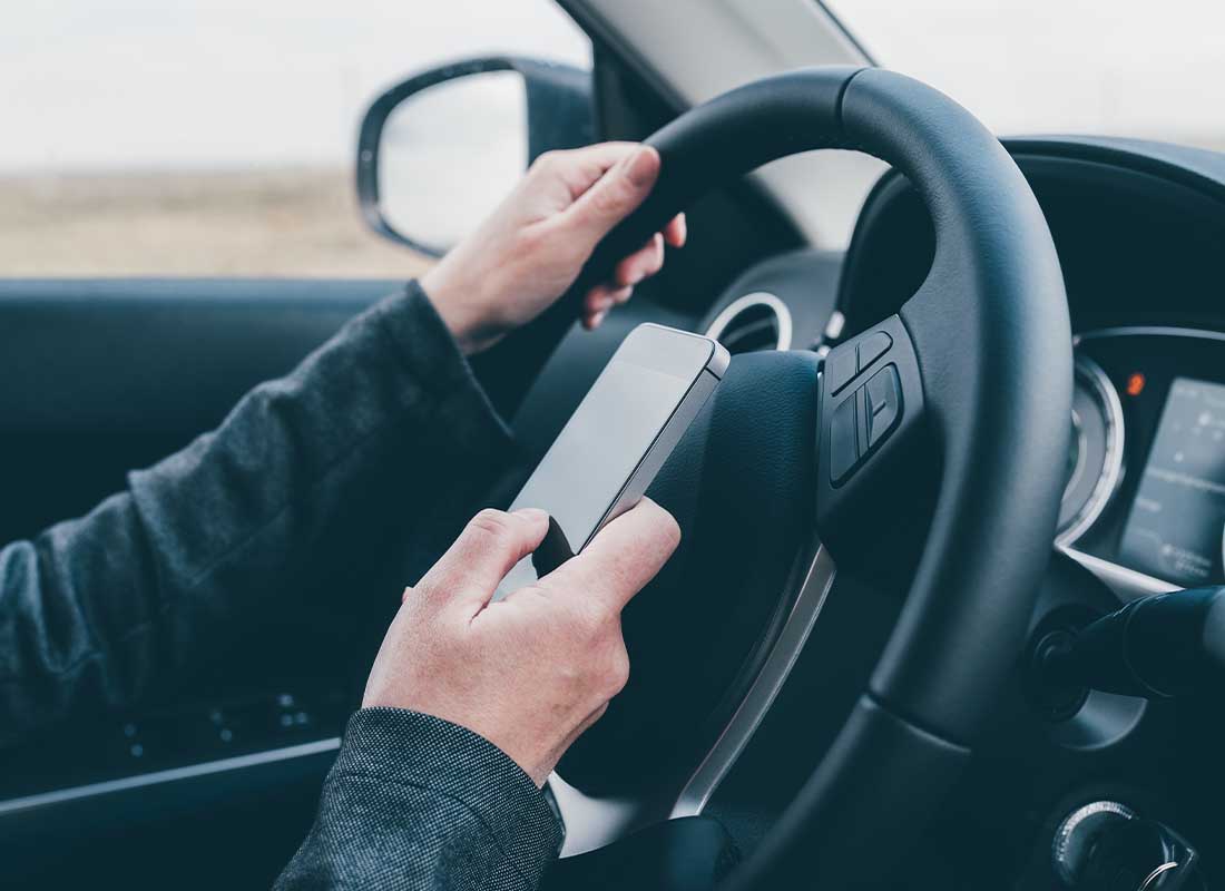 SR-22 - Close-up of a Reckless Driver Texting While behind the Wheel of a Moving Vehicle